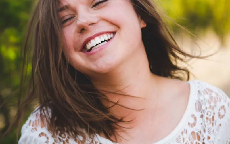 Person smiling confidently with straight teeth after completing Invisalign treatment at Dr. Baldwin's Huntington Beach office