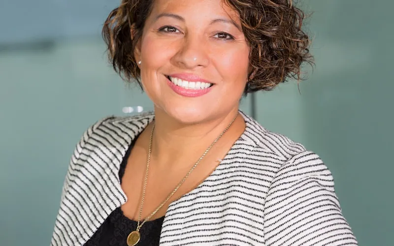 Professional woman smiling confidently at work, showing how Invisalign fits seamlessly into daily life
